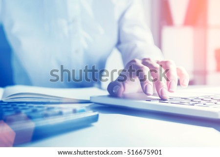Close up of woman's hand in office who is typing on the laptop keyboard. Concept of secretary work. Toned image