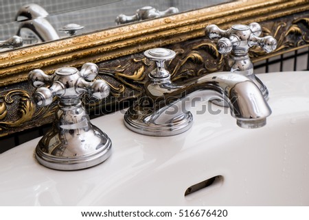 Vintage silver water tap with golden frame in the bathroom