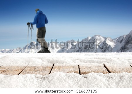 wooden desk of free space for your decoration of product or text and skier on top of mountains in Alps with blue sky of december time. 