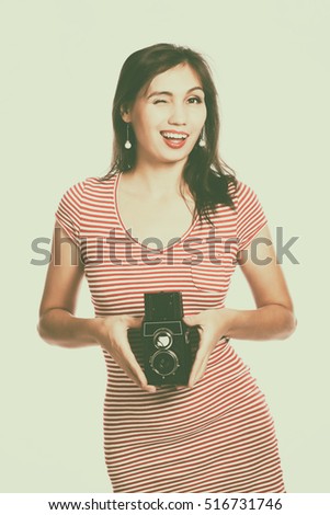 Portrait of a young woman taking a picture with a camera. Toned