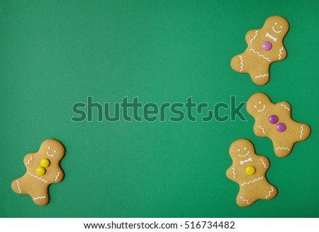 Hand decorated gingerbread men on a green background with blank space in the middle