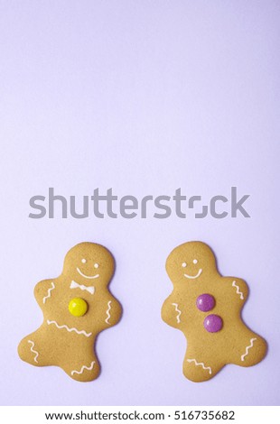 Hand decorated gingerbread men on a pastel purple background with empty space above