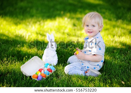 Little boy hunting for easter egg in spring garden on Easter day. Cute little child with traditional bunny celebrating feast