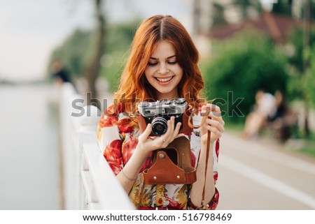 
Woman photographer. The woman with the camera. Lovely girl in nature takes on the old camera