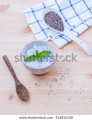 Nutritious chia seeds in ceramic bowl with wooden spoon for diet food ingredients setup on wooden background . shallow depth of field.