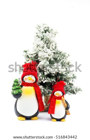 Two penguin figurines with christmas tree in winter