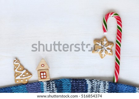 flat layout of a wooden house on a warm scarf and striped candy and cookies top view / street sweet fairy lanterns