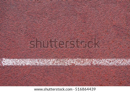Texture of rubber running track on the stadium, athletics sport background, top view of red racetrack surface with white stripe