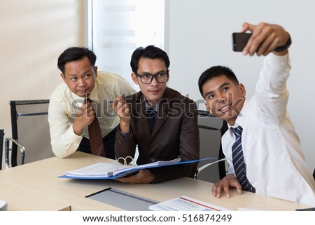 Young people making group photo with smart phone in office.
Group of young businessmen are shooting themselves.