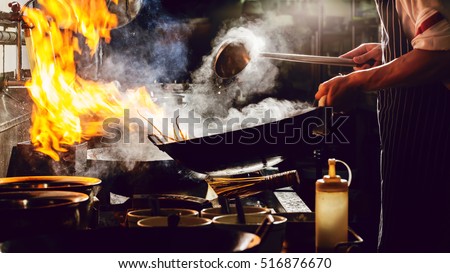 Chef is stirring vegetables  in wok on street food concept Royalty-Free Stock Photo #516876670