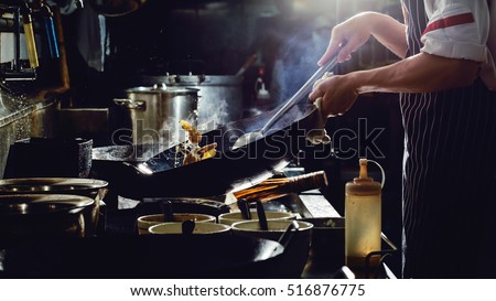 Chef is stirring vegetables  in wok on street food concept Royalty-Free Stock Photo #516876775