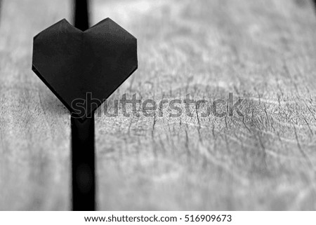 Paper black heart on the wooden background.