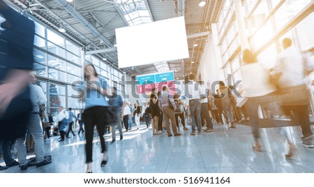 Blurred trade fair visitors walking in hall