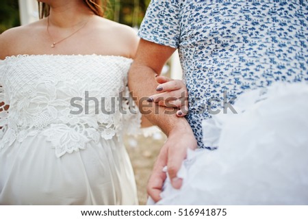Happy pregnant couple stay  near decor arch at garden and hold decoration clouds on hand