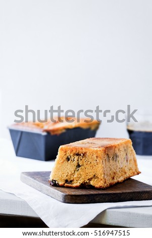 Orange loaf cake with chocolate.  Dark wooden board. White background. Copy space. High key food photography.