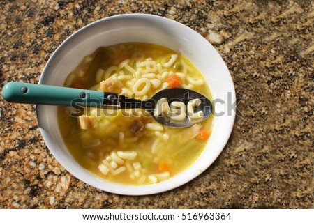 bowl of alphabet soup on counter with abc spelled out on spoon Royalty-Free Stock Photo #516963364