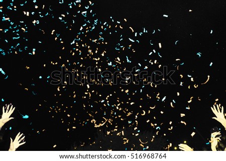 Yellow/green confetti fired in the air during a beach party. Hands in the air on both sides of the pic