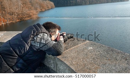 Intentional blur.
Photographer with camera making a panoramic photo of a dam.