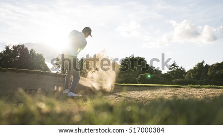 Man in bunker playing golf on a golf course in the sun