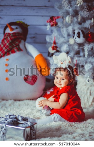 The small girl sits near christmas tree