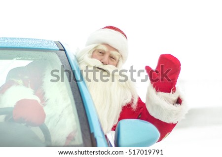 Funny Santa Claus peeking out of the car and congratulating waving