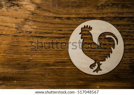 Wooden white rooster in round. New Year. Cock under white snow flakes lie on wooden board background. empty copy space for inscription or other objects. Idea of happy new year on the eastern calendar