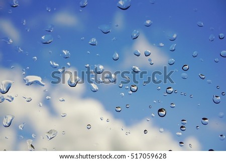 water drop on window with background of blue sky and clouds