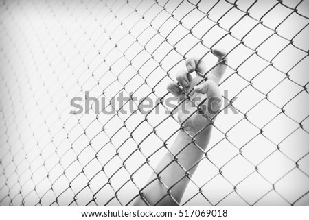 Hand catching mesh cage. The prisoner want freedom. Man lack of Independence.
Black and white 