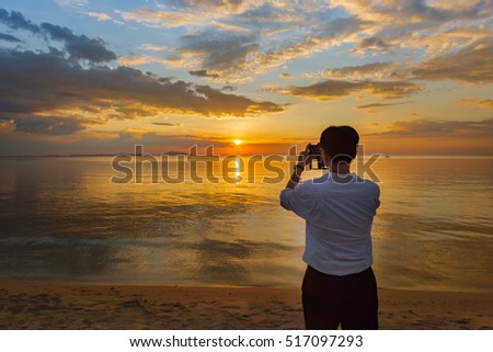 Business man use smartphone take a picture of sunset