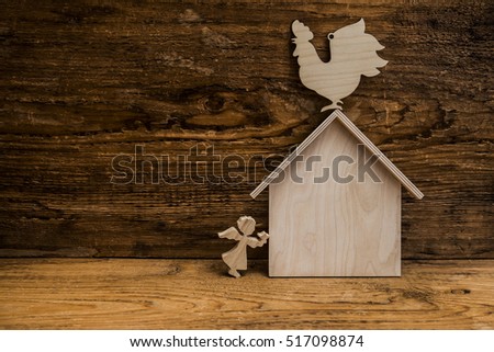 wooden house with rooster on roof. Christmas star in hands of angel. Wooden figure stand on top of sign of house. European holiday traditions. Christmas concept. 2017 happy new year of rooster
