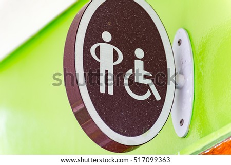 Accessible or handicapped bathroom sign vintage style. 
Close up on oval shaped accessible or handicapped restroom sign bolded to green wall on cruise ship