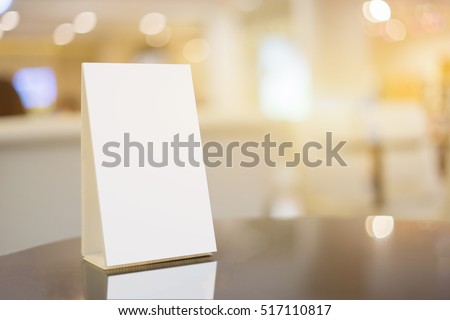 Mock up Menu frame on Table in Bar restaurant ,Stand for booklets with white sheets of paper acrylic tent card on cafeteria blurred background