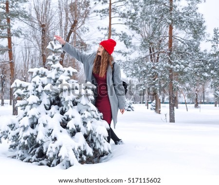 Portrait of pretty attractive girl hipster winter park. She and a Christmas tree in the snow. Youth street fashion. Winter fun. Walks in the open air.