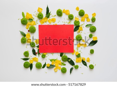 Red paper with wreath frame from rose and chrysanthemum flowers, ficus leaves and ripe rowan on white background. Overhead view. Flat lay.
