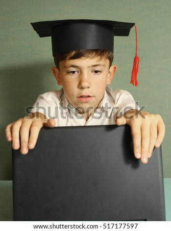 preteen boy in graduation hat opening laptop close up photo