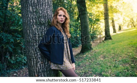 Beautiful portrait of young redhead woman outdoors in a park in autumn.