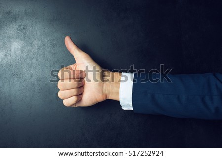Like this. Close-up of human hand with thumb up in front of the blackboard Royalty-Free Stock Photo #517252924