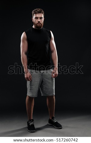 Full length trainer. looking at camera. isolated dark background