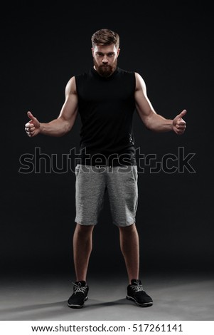Full length portrait of trainer. show fingers up. isolated dark background