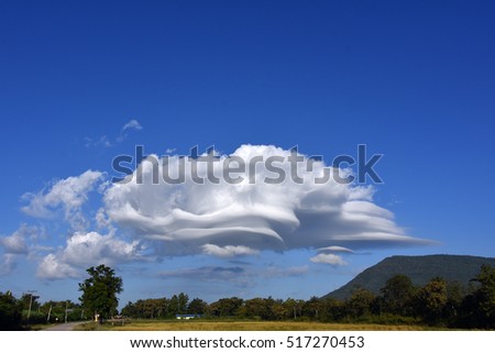 lenticular wind cloud resembling a UFO flying saucer over  mountain in countryside , thailand  Royalty-Free Stock Photo #517270453