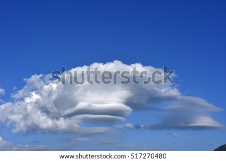 lenticular wind cloud resembling a UFO flying saucer over  mountain in countryside , thailand  Royalty-Free Stock Photo #517270480