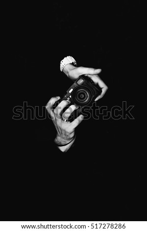 A man photographer holding a camera. Retro camera on a black background.