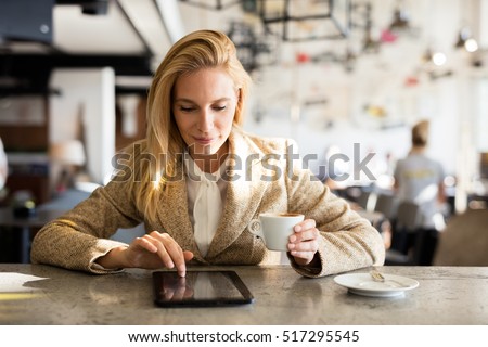 Modern business woman in city cafe. Drinking coffee and surfing the web. Coffee break. Royalty-Free Stock Photo #517295545