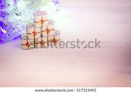Little Chocolate Sweets in a Form of Gift Boxes on Wooden Texture with Christmas Lights. Holiday background. Merry Christmas and a Happy New Year Card with Space for Text.