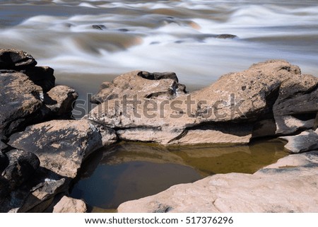 The rocks with long exposure water wave in the river.