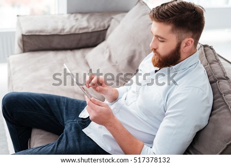 Man with tablet on sofa. side view