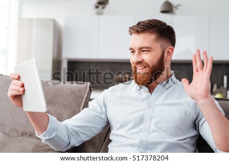 Happy man with tablet on sofa. looking at tablet