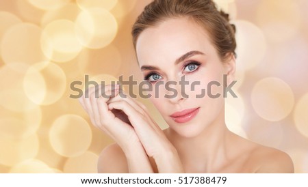 beauty, people, holidays and skin care concept - beautiful young woman face and hands over beige lights background