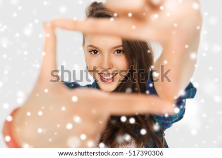 winter, christmas, photorgaphy, people and teens concept - happy smiling pretty teenage girl making frame of fingers over gray background and snow