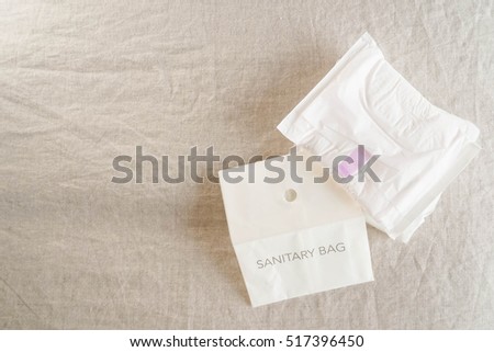 Sanitary napkins and sanitary bag (paper bag). window light, isolated on bed sheet. femininity, adulthood and menstrual concept